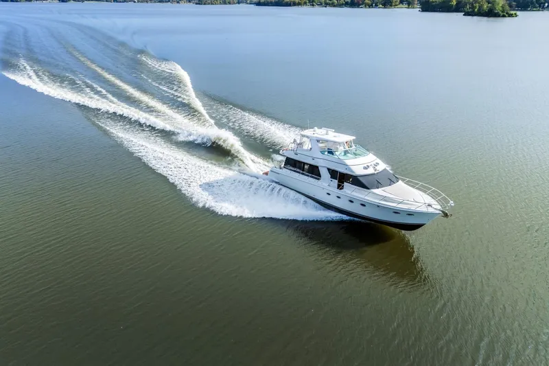 Slide: The Image of 2004 Carver 570 Voyager Pilothouse cruising on a calm lake, leaving a wake. - 3