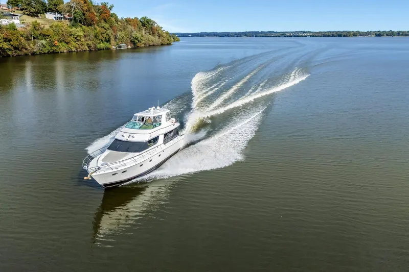 Slide: The Image of 2004 Carver 570 Voyager Pilothouse cruising on a serene lake with lush shoreline. - 4