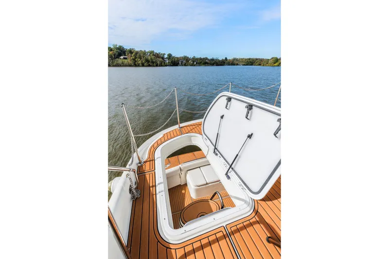 Slide: The Image of 2004 Carver 570 Voyager Pilothouse yacht deck with open hatch, overlooking serene water. - 52