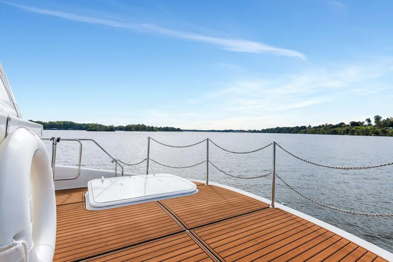 Slide: The Image of 2004 Carver 570 Voyager Pilothouse yacht deck overlooking serene water and clear blue sky. - 53