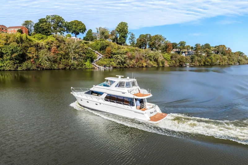 Slide: The Image of 2004 Carver 570 Voyager Pilothouse cruising on a scenic river with lush green banks. - 6