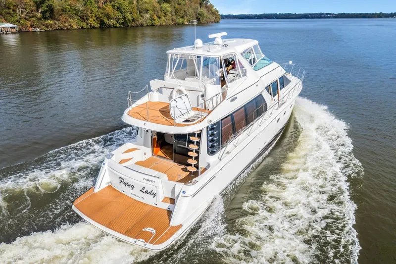 Slide: The Image of 2004 Carver 570 Voyager Pilothouse yacht cruising on a serene river. - 7