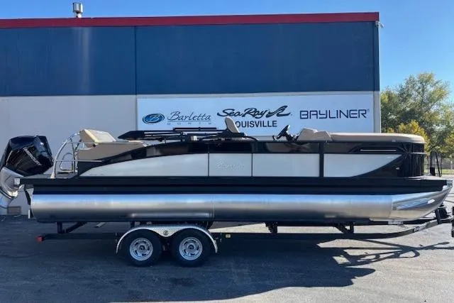 The Image of 2026 Barletta C24UE pontoon boat on trailer, parked outside dealership. - 1