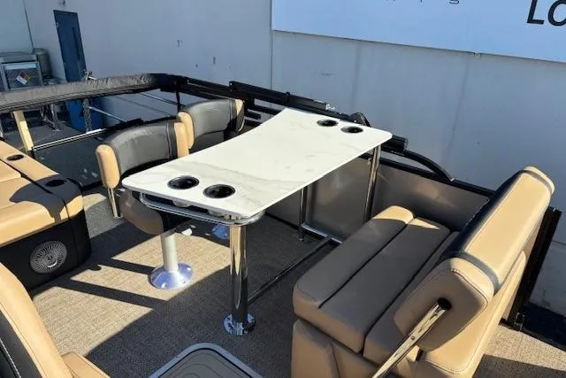 Slide: The Image of 2026 Barletta C24UE pontoon boat interior with beige seating and a table with cup holders. - 8