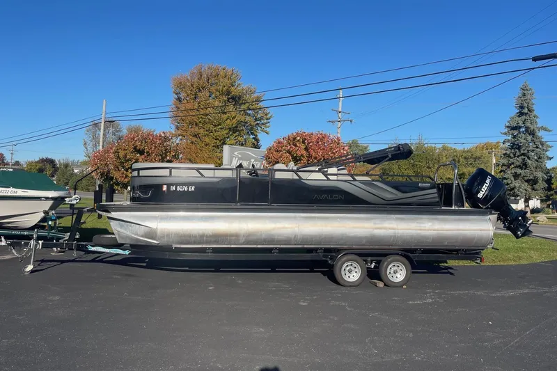 The Image of 2025 Avalon Venture 2585 VRB pontoon boat on trailer, parked outdoors under clear blue sky. - 1