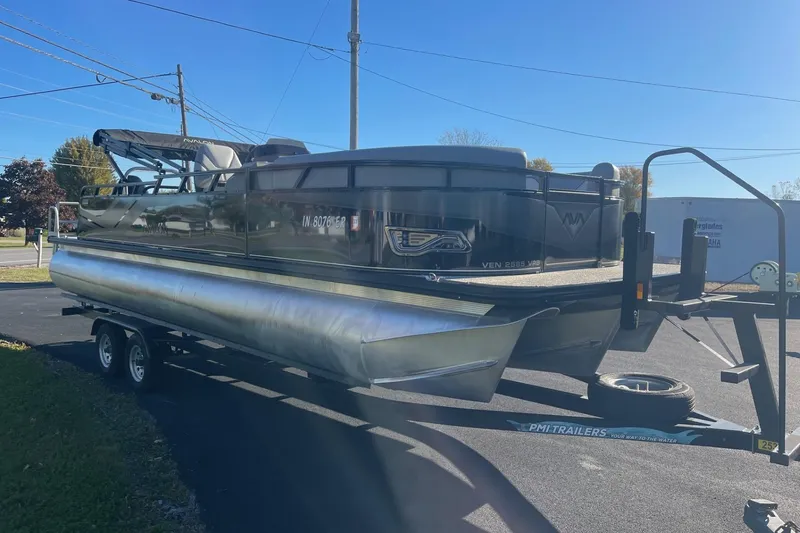 Slide: The Image of 2025 Avalon Venture 2585 VRB pontoon boat on trailer, parked outdoors. - 3