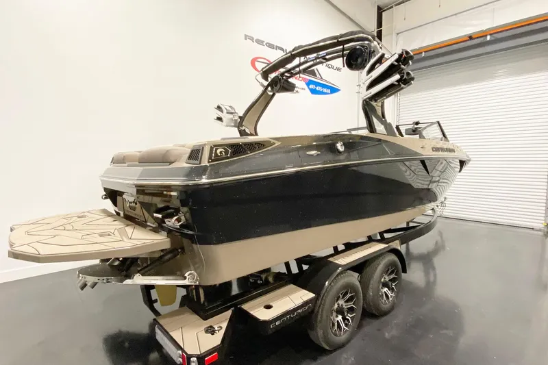 The Image of 2025 Centurion Fe22 boat on trailer in showroom, featuring sleek black and tan design. - 1