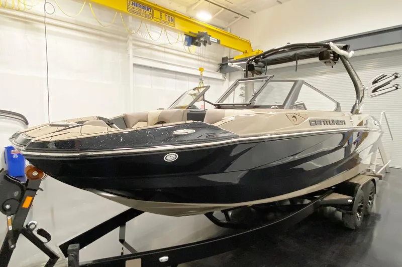 Slide: The Image of 2025 Centurion Fe22 boat in showroom, black and beige design, on trailer. - 6