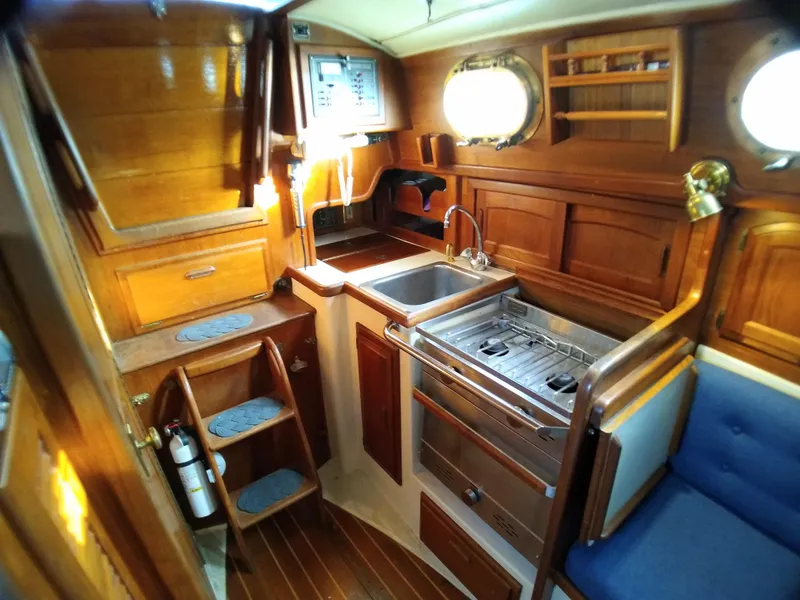 Slide: The Image of Interior of a 1988 Pacific Seacraft Dana 24 yacht, featuring wood finish and kitchen. - 26