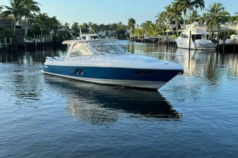 Slide: The Image of 2019 Intrepid 430 Sport Yacht cruising on a serene, palm-lined waterway. - 0