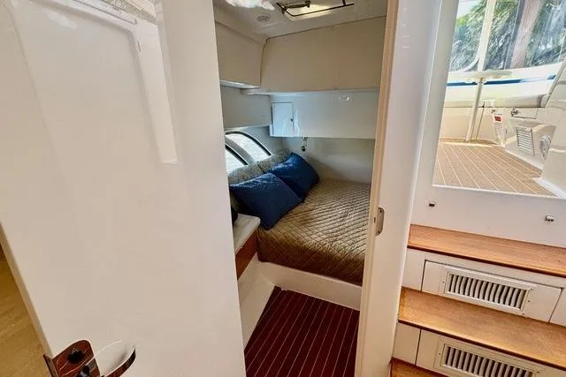 Slide: The Image of 2019 Intrepid 430 Sport Yacht cabin with cozy bed and wooden steps. - 14