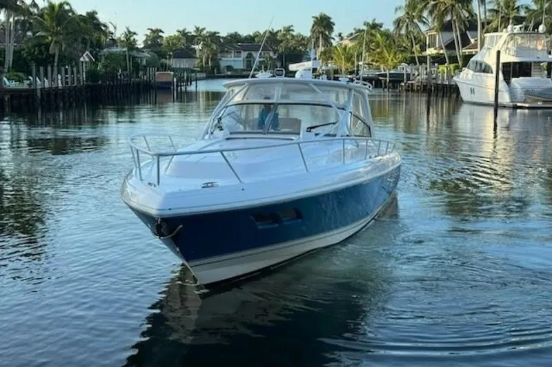 Slide: The Image of 2019 Intrepid 430 Sport Yacht cruising in a serene, palm-lined waterway. - 7