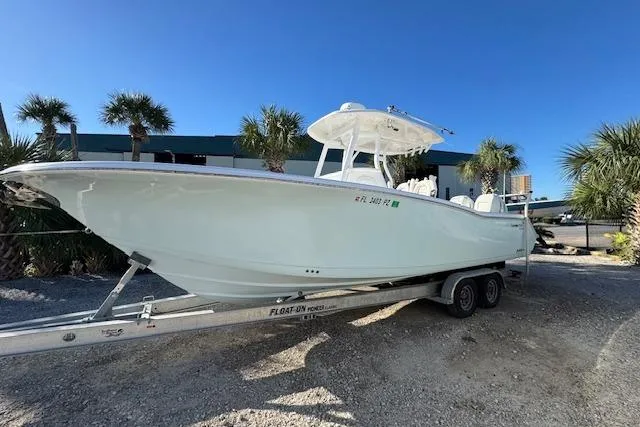 The Image of 2015 Tidewater 280 CC Adventure boat on trailer, parked outdoors under clear blue sky. - 1