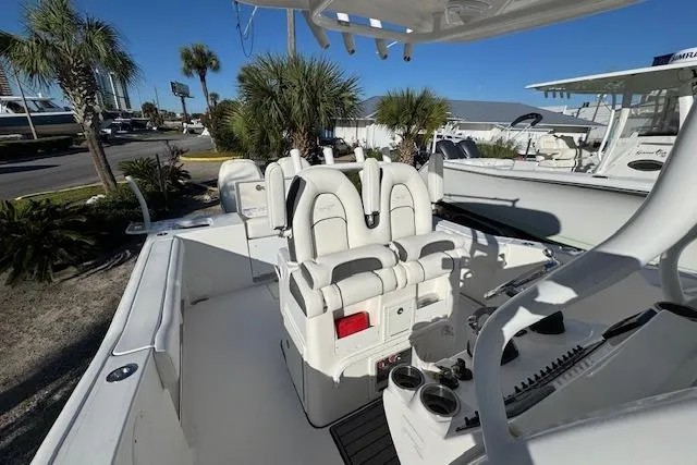 Slide: The Image of 2015 Tidewater 280 CC Adventure boat interior with seating and console, surrounded by palm trees. - 10