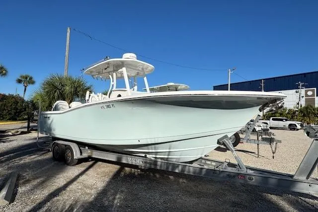 Slide: The Image of 2015 Tidewater 280 CC Adventure boat on trailer, parked outdoors under clear blue sky. - 6