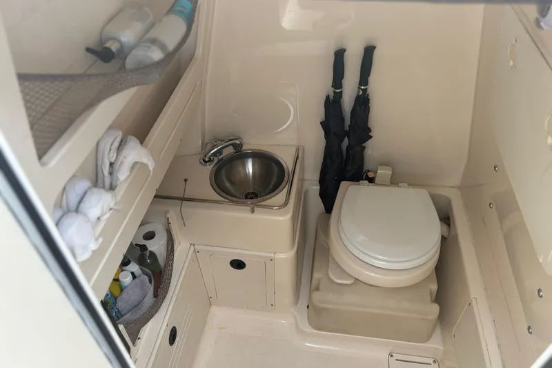 Slide: The Image of 2013 Scout 275 LXF boat interior with sink, toilet, and storage shelves. - 19