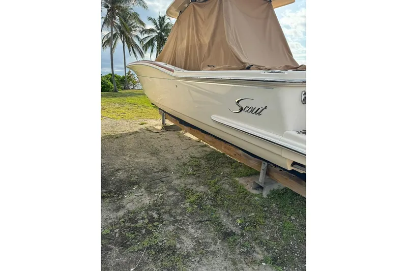 Slide: The Image of 2013 Scout 275 LXF boat on land with cover, palm trees in background. - 3