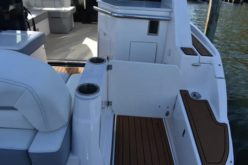 Slide: The Image of 2024 Regal 36 XO boat interior with seating and cup holders, docked by water. - 11