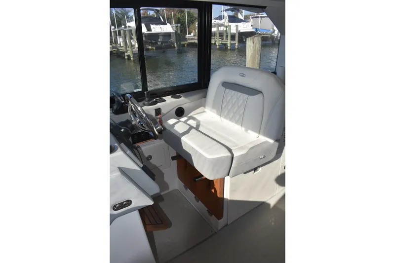 Slide: The Image of 2024 Regal 36 XO helm seat with steering wheel, docked by the water. - 36