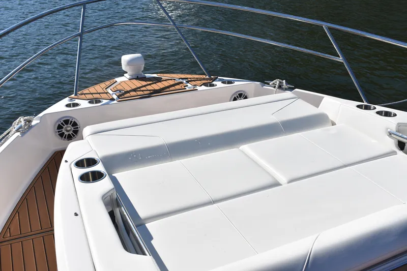 Slide: The Image of 2024 Regal 36 XO boat deck with white seating and cup holders on water. - 40