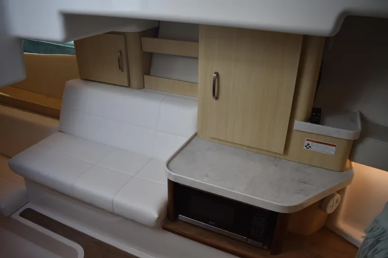 Slide: The Image of 2024 Regal 36 XO interior with white seating, wooden cabinets, and a compact kitchen area. - 57