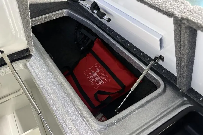 Slide: The Image of Open storage compartment in 2024 Phoenix 920 Elite boat with red bag inside. - 14
