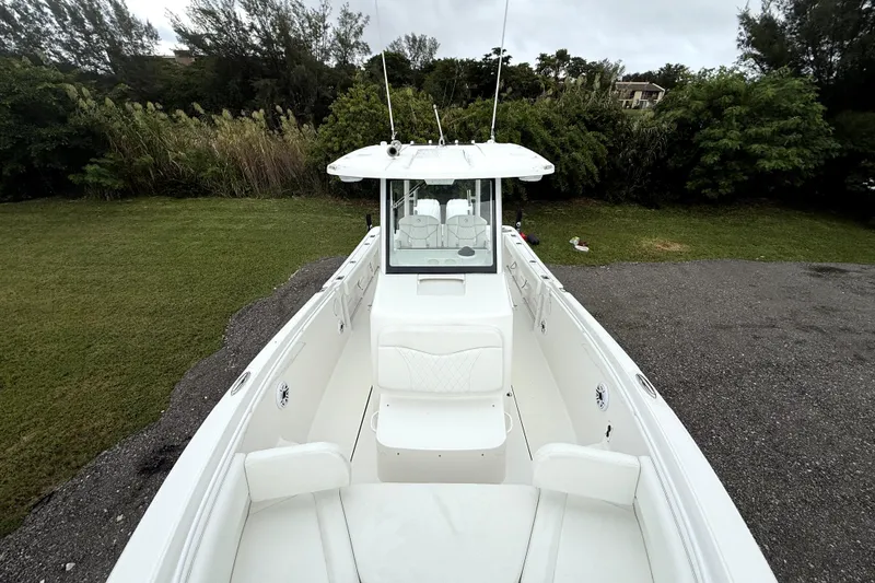 Slide: The Image of 2023 Edgewater 285CC boat, white interior, parked on grass with trees in background. - 10