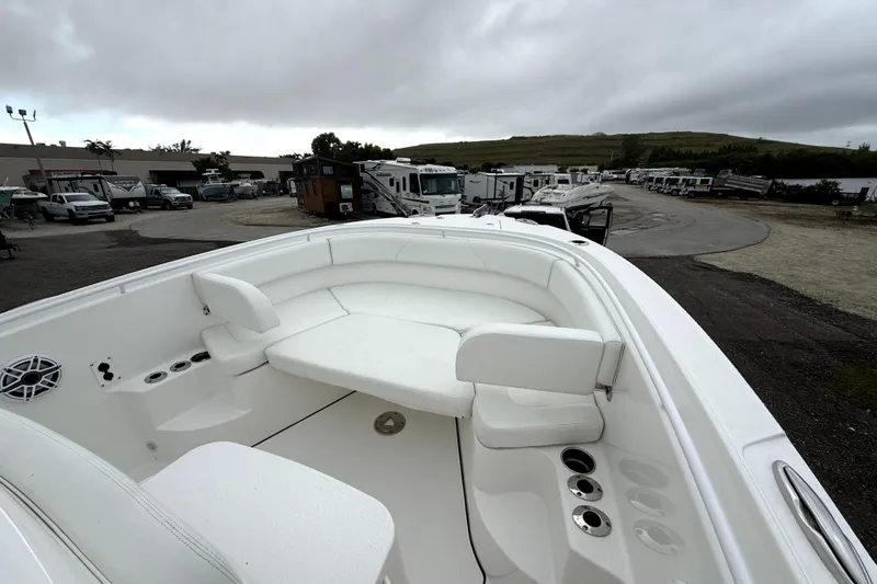 Slide: The Image of 2023 Edgewater 285CC boat interior with white seating, parked in a dealership lot. - 18