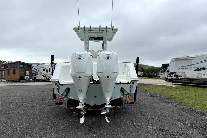 Slide: The Image of 2023 Edgewater 285CC boat with dual outboard motors, parked in a lot. - 3