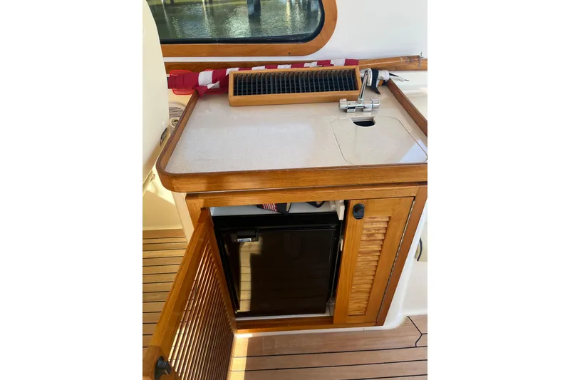 Slide: The Image of 2004 Sabre 42 Hardtop Express interior with wooden cabinetry and mini fridge. - 10