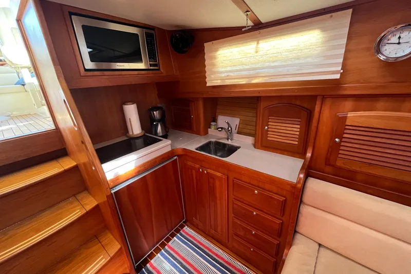 Slide: The Image of 2004 Sabre 42 Hardtop Express yacht kitchen with wood cabinetry, microwave, and sink. - 16