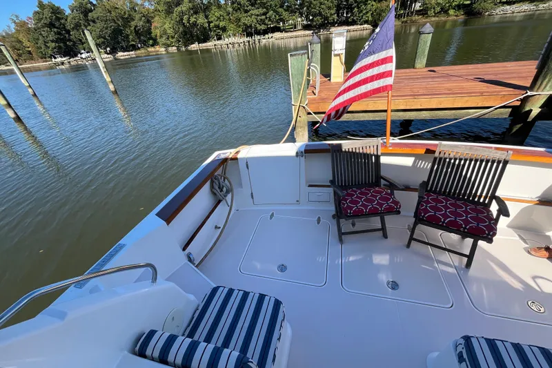 Slide: The Image of 2004 Sabre 42 Hardtop Express boat deck with chairs and American flag by the dock. - 2