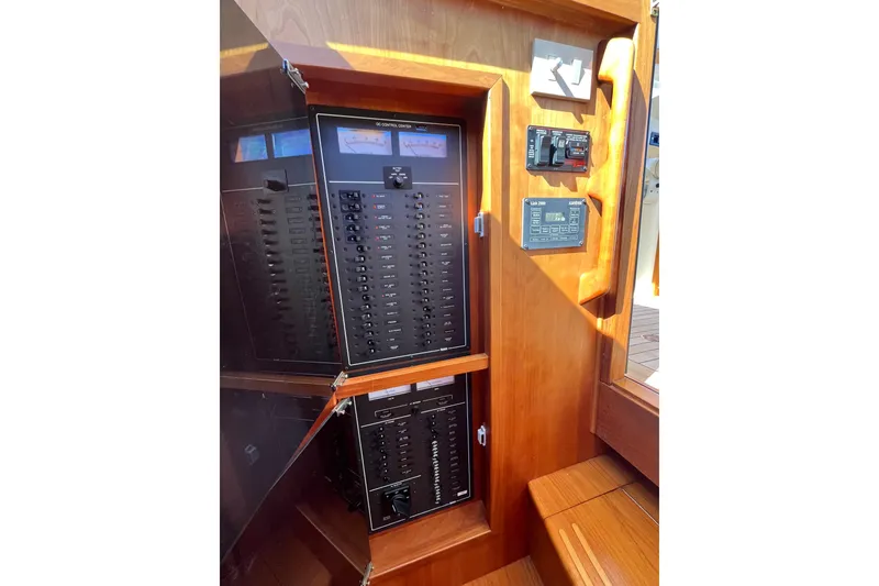 Slide: The Image of Electrical control panel inside 2004 Sabre 42 Hardtop Express yacht, featuring wooden cabinetry. - 23