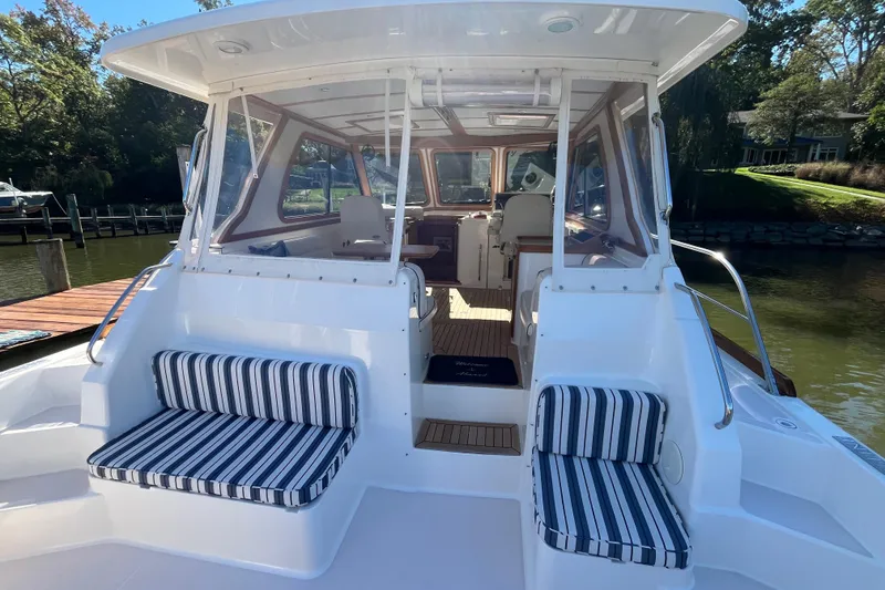 Slide: The Image of 2004 Sabre 42 Hardtop Express boat with striped seating, docked by a serene waterfront. - 3