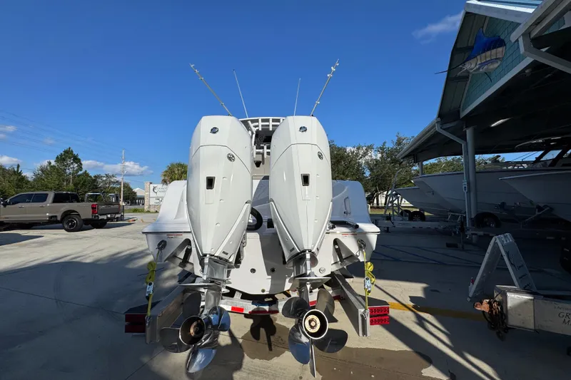 Slide: The Image of 2024 Sportsman Open 302 Center Console boat with dual outboard engines in a marina. - 11