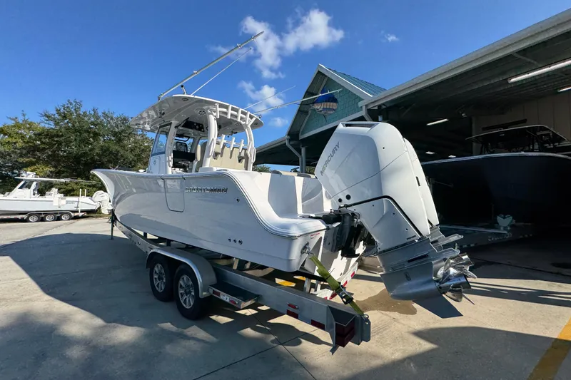 Slide: The Image of 2024 Sportsman Open 302 Center Console boat on trailer, featuring dual outboard engines. - 13