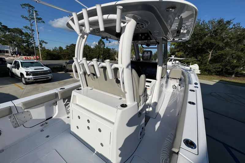 Slide: The Image of 2024 Sportsman Open 302 Center Console boat with rod holders and seating, parked outdoors. - 41