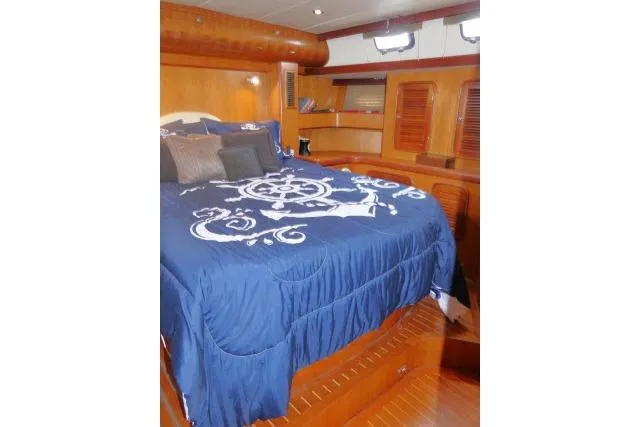 Slide: The Image of 2006 Tayana 58 Deck Salon bedroom with wooden interior and patterned bedding. - 29