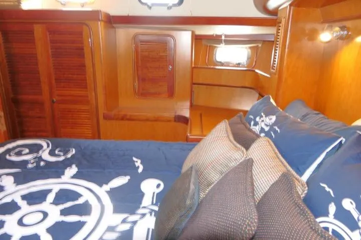 Slide: The Image of Luxurious 2006 Tayana 58 Deck Salon interior with nautical-themed bedding and wooden cabinetry. - 31