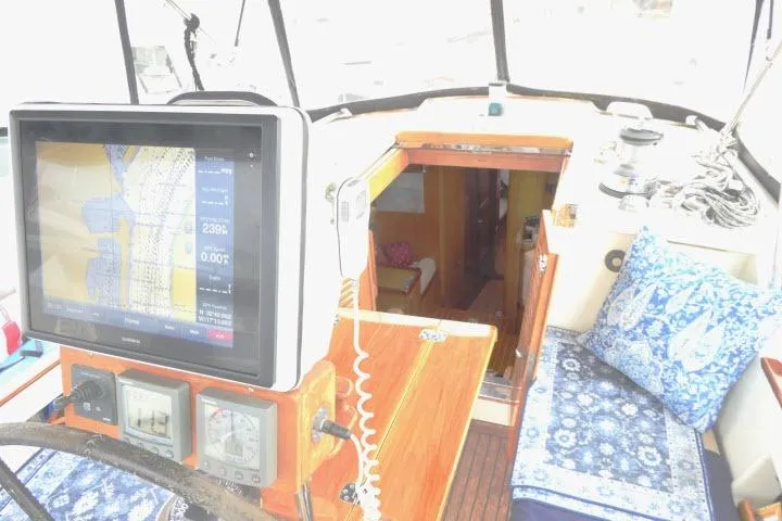 Slide: The Image of 2006 Tayana 58 Deck Salon interior with wooden table, blue cushions, and navigation equipment. - 43