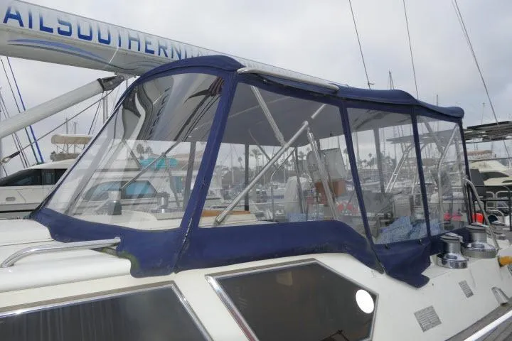 Slide: The Image of 2006 Tayana 58 Deck Salon yacht docked at marina, featuring spacious deck and clear canopy. - 48