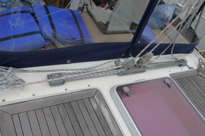 Slide: The Image of 2006 Tayana 58 Deck Salon sailboat docked in a marina, featuring a visible boom and rigging. - 54