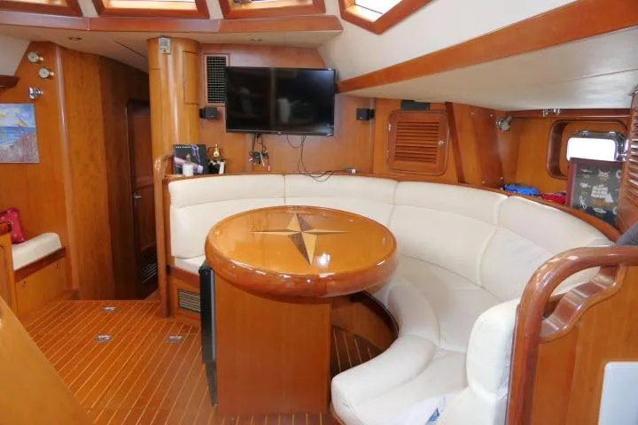 Slide: The Image of Interior of 2006 Tayana 58 Deck Salon yacht with curved seating and wooden table. - 7
