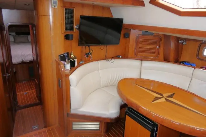 Slide: The Image of 2006 Tayana 58 Deck Salon interior with curved seating and wooden table. - 8