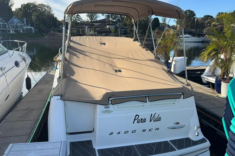 The Image of 2003 Maxum 2400 SCR boat docked with beige cover, named "Pura Vida." - 0