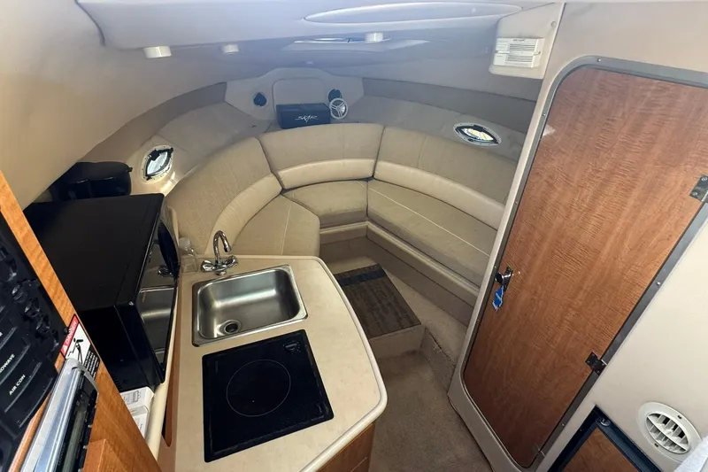 Slide: The Image of 2003 Maxum 2400 SCR boat with white seating and wooden table, docked at marina. - 10