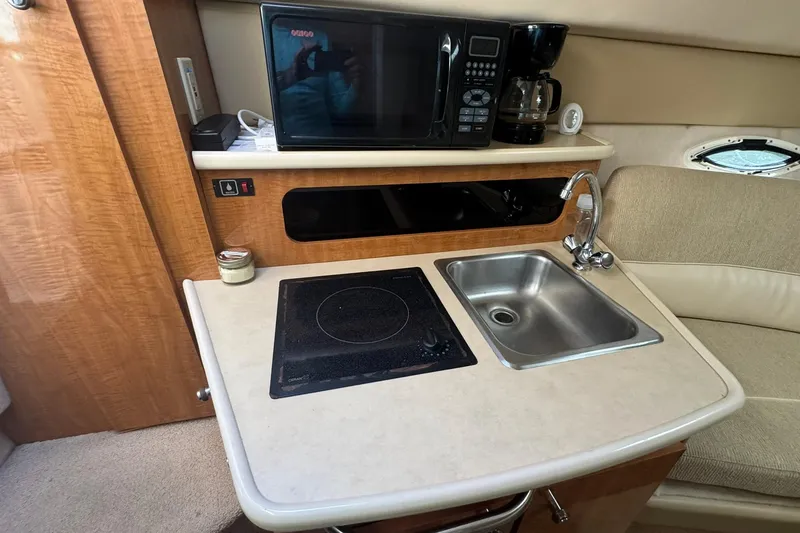 Slide: The Image of 2003 Maxum 2400 SCR boat interior with kitchenette, featuring sink, stove, microwave, and coffee maker. - 23