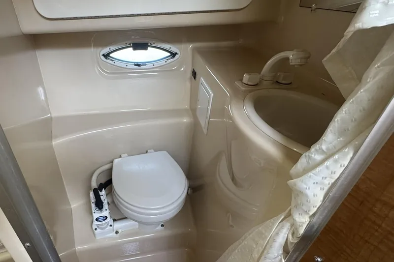 Slide: The Image of 2003 Maxum 2400 SCR boat bathroom with toilet, sink, and porthole window. - 28