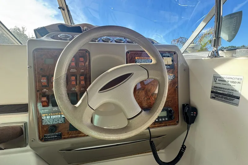 Slide: The Image of 2003 Maxum 2400 SCR boat interior with seating and steering wheel in marina. - 6