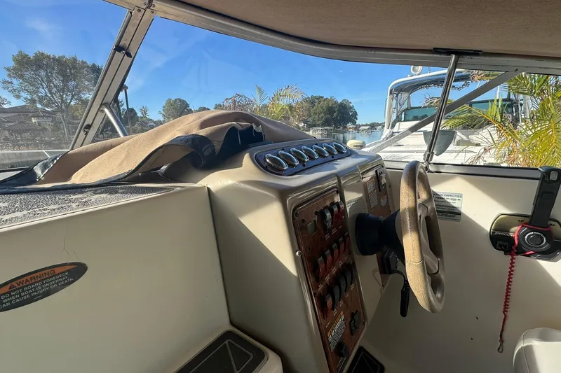 Slide: The Image of 2003 Maxum 2400 SCR boat interior with white seating and wooden table at dock. - 8